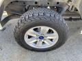 Close-up of a silver alloy wheel with a rugged tire of a 2018 Ford F-150 showing detailed tread patterns and the Ford logo in the center cap