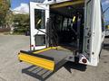 A 2018 Ford Transit-350 with a wheelchair lift extended and positioned at the rear entrance of the vehicle