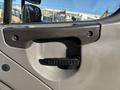 Close-up of the door handle of a 2005 Freightliner M2 106 featuring a textured grip and a simple design with screws visible on the surrounding panel