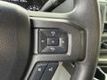 Close-up of the steering wheel controls in a 2022 Ford E-450 featuring buttons for volume and media navigation