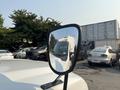A 2009 Ford F-550 is reflected in the side mirror of the vehicle with a white exterior and a distinct front grille