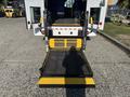 A 2017 Ford Transit-350 wheelchair lift ramp extended with a yellow and black surface and safety markers visible on the sides