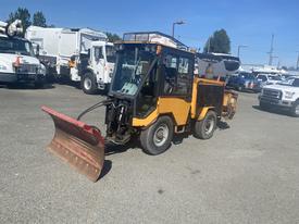 A 2010 Trackless MT6 utility vehicle with a front-mounted snowplow attachment in a parking lot