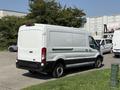 A white 2022 Ford Transit van parked with a blank rear door and black lower trim on the side