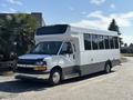 A white 2020 Chevrolet Express shuttle bus with large windows and a high roof parked on a driveway