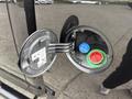 Close-up of the fuel filler door on a 2018 RAM 1500 featuring a black exterior cap with a green and blue nozzles inside