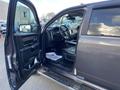 A 2017 RAM 1500 with the driver's side door open revealing the interior and dashboard details including leather seats and a modern steering wheel