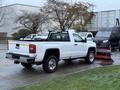 A white 2017 GMC Sierra 3500HD pickup truck with a flatbed and a metal grille guard on the back in a parking area