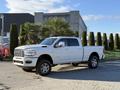 A white 2023 RAM 3500 pickup truck with chrome wheels and a spacious cab parked with a tall bed and distinctive grille design