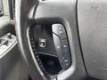 Close-up of the steering wheel of a 2022 GMC Savana featuring control buttons for cruise settings and a leather-wrapped grip