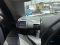 A digital gauge mounted on the dashboard displaying a numerical reading with a blue button on its side