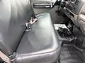 A black rear bench seat of a 2000 Ford F-450 with seatbelts and an adjustable armrest visible in the foreground