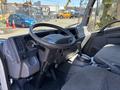 Interior view of a 2022 Isuzu NQR showing the dashboard steering wheel and gear shift with fabric-covered seats