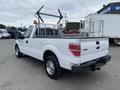 A white 2013 Ford F-150 truck with a utility bed and a metal rack on the back