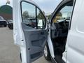 A white 2017 Ford Transit van with its driver's side door open showcasing the interior dashboard and seating area