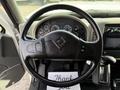 A black steering wheel with controls on the left side and a dashboard displaying various gauges and indicators in the background
