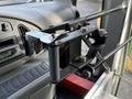 A black metal assembly with bolts and a lever attached to a vehicle interior, resembling a mount for holding equipment or accessories