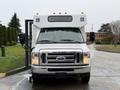 A 2017 Ford E450 shuttle bus with a white exterior and accessible features including wheelchair symbols on the front