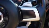 Close-up of the steering wheel in a 2007 Mazda Miata featuring metallic paddle shifters labeled UP and DOWN