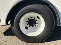 A close-up view of a tire mounted on a white rim designed for a 2005 Freightliner M2 106 with visible tread patterns and lug nut design