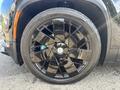 A close-up view of a black alloy wheel on a 2023 Fisker Ocean featuring a unique multi-spoke design and low-profile tire visible