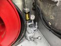 A 2011 Ford F-550's engine compartment featuring a pressure gauge and a valve with a handle next to a coiled hose