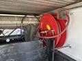 A red hose reel with hoses is mounted on a black wooden surface in the back of a vehicle