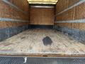 A 2012 Mitsubishi Fuso FE truck with an empty cargo area featuring wooden walls and a wooden floor with some visible stains and marks