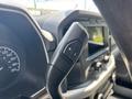 A close-up of the gear shift lever in a 2021 Ford F-150 featuring buttons for shifting gears with plus and minus symbols