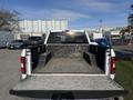 A white 2018 Ford F-150 with its tailgate down showing an empty truck bed and side storage compartments