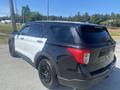 A 2020 Ford Explorer with a black and white exterior parked in a clear area, showcasing its distinctive rear design and alloy wheels