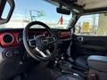 Interior view of a 2021 Jeep Wrangler showcasing the steering wheel dashboard and gear shifter with a red accent around the dashboard and black seating