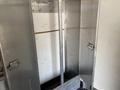 An empty metal locker with two hooks on the inside walls and a large compartment at the bottom for storage
