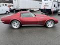 A 1970 Chevrolet Corvette in a deep red color with a sleek design and chrome accents featuring distinctive round headlights and a sporty profile