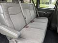 A gray interior of a 2004 Chevrolet Express featuring a three-seat bench with seat belts and armrests on either side