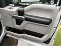 Interior door panel of a 2015 Ford F-150 featuring a grey and black color scheme with a handle and storage space