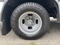A close-up of a silver wheel with a rugged black tire mounted on a Chevrolet Express van