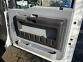 Interior door panel of a 2010 Ford F-450 featuring a gray surface with a handle and a storage compartment