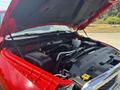 A 2013 RAM 2500 engine with the hood open showing various components such as the air intake system and battery situated on a red truck's engine bay