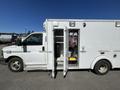A 2013 Chevrolet Express with open side doors revealing interior equipment and wiring