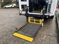 A 2021 Ford Transit-350 with a retractable wheelchair lift extended at the rear showing yellow and black safety markings