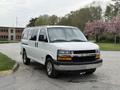 A white 2004 Chevrolet Express van parked with its front facing the viewer showing a black grille and silver wheels