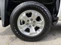 Close-up of a silver wheel and tire from a 2018 Chevrolet Silverado 1500 featuring a five-spoke design and all-terrain tread pattern