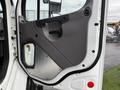 A close-up view of the door of a 2015 Freightliner M2 featuring a gray panel with a handle and a rectangular window on the lower part of the door