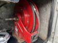 A red fire hose reel mounted inside a vehicle with a black hose coiled around it