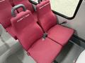 Two maroon seats with seat belts in a bus interior, labeled with names on the backrest