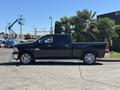 A black 2015 RAM 1500 pickup truck with chrome accents and large wheels is parked, showcasing its side profile and spacious cab design