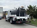 A 2016 Peterbilt 348 truck with a large black tank attached to the back and safety lights on the cab
