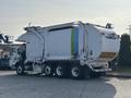 A 2011 Autocar Xpeditor garbage truck with a white body and colorful stripes along the side parked on a paved area