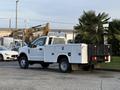 A white 2018 Ford F-350 truck with a flatbed and utility body parked with visible rear taillights and no visible markings on the side